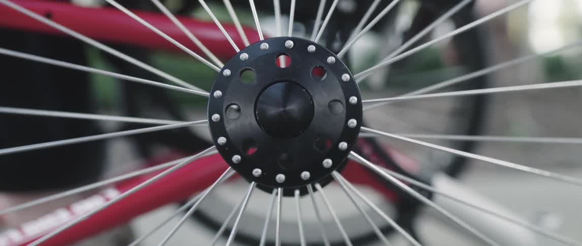 A man reaches down to spin the spokes on his bicycle