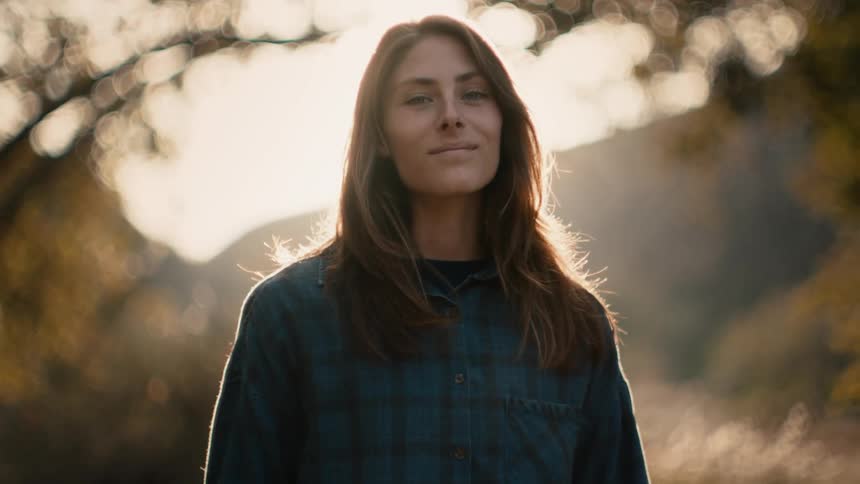 A woman poses outside by the trees