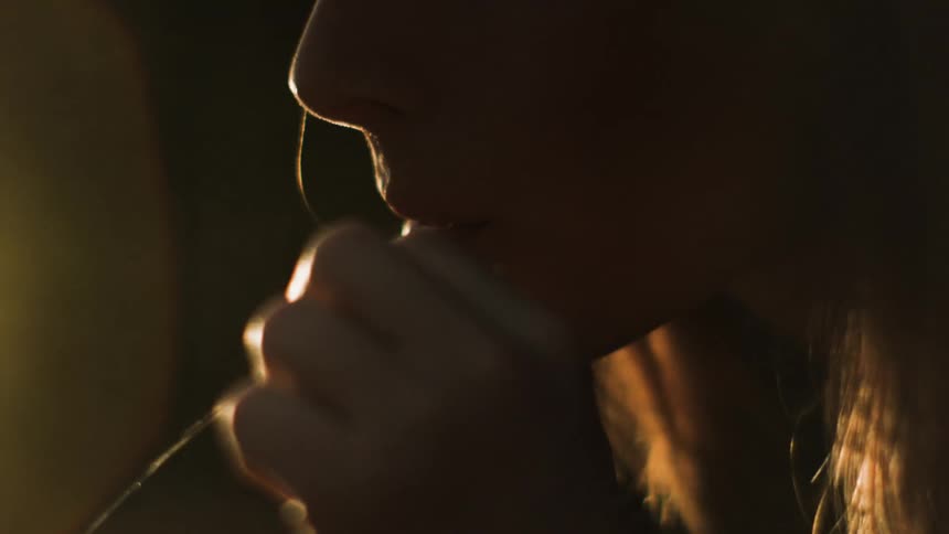 A woman chews on a piece of grass