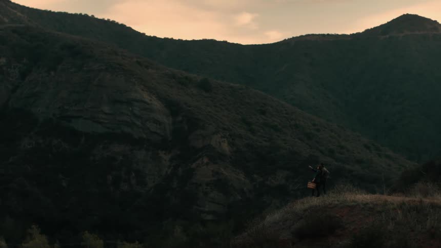 Two hikers stop on a cliff to take in views of nearby mountains