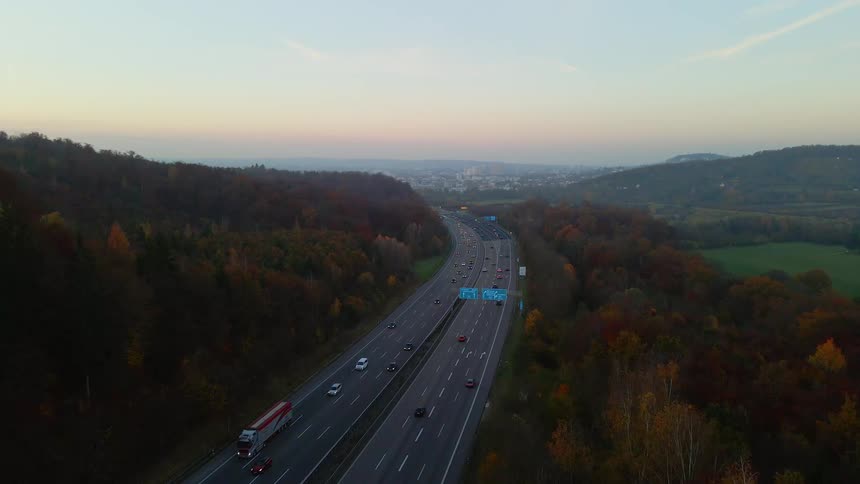 Aerial view of a busy highway surrounded by trees and buildings in the distance