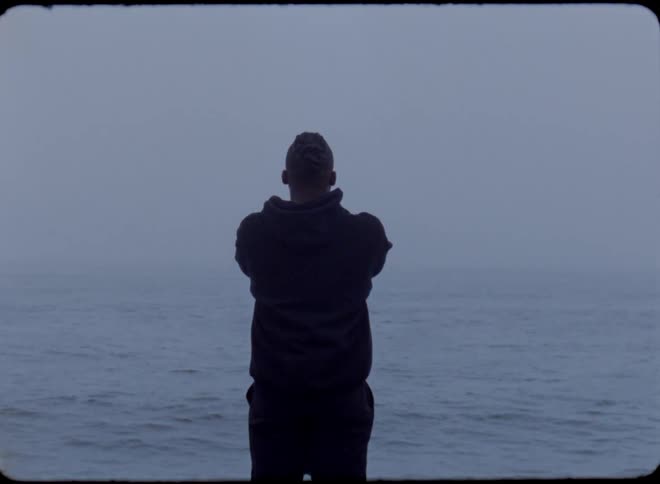 Man stands between gates on shore facing horizon over ocean