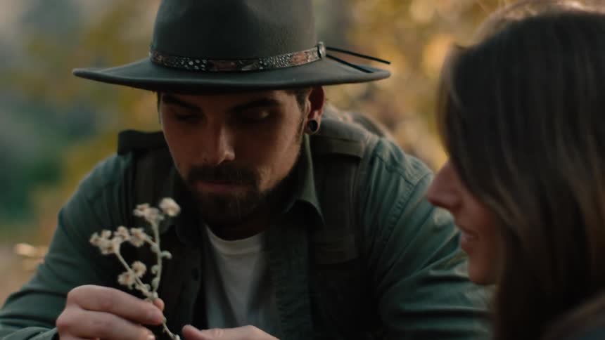 A man shows a woman a small flower