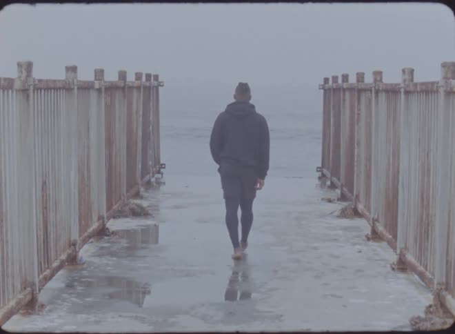 A man walks on the boardwalk towards the ocean