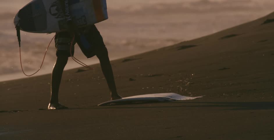 A person carrying a surfboard on the beach