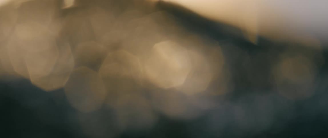 Close up of blurry small ocean wave with sunlight in the background