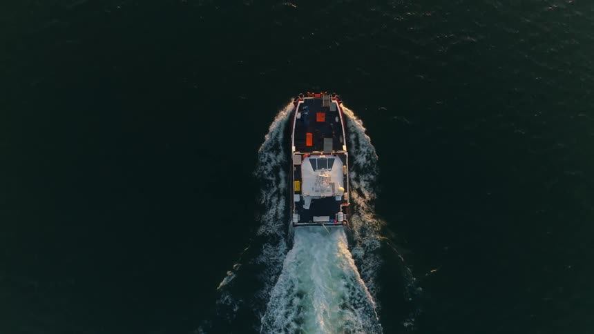 A boat with turning antenna cuts through the ocean leaving a foaming wake