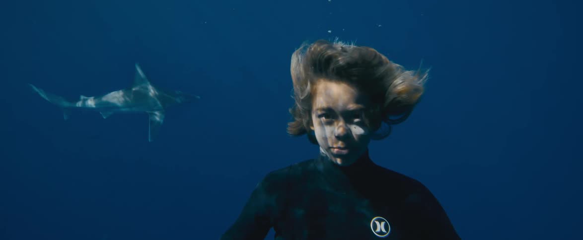 A young man is underwater and a fish is swimming near him