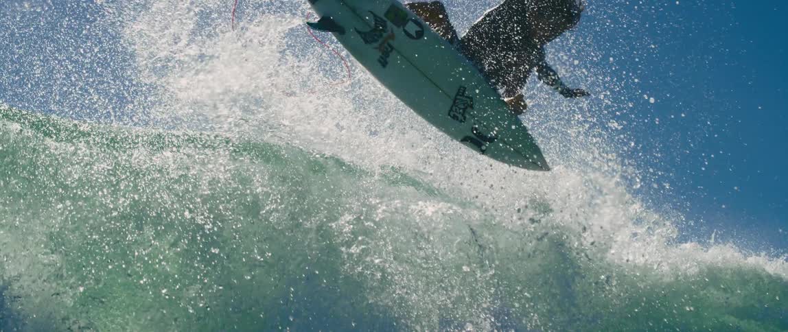 Ocean water splashes and flies as a surfer twirls midair and splashes down