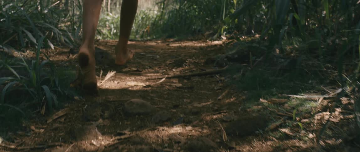 A person running barefoot through a forest
