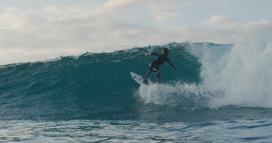 A man jumps and spins while riding the wave on a surfboard