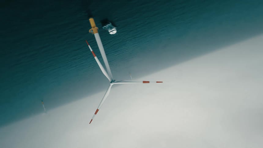 A spinning wind turbine on the ocean on a cloudy day