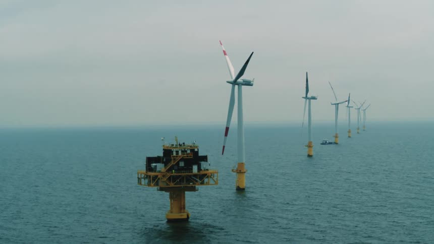 An aerial view of windmills on the water
