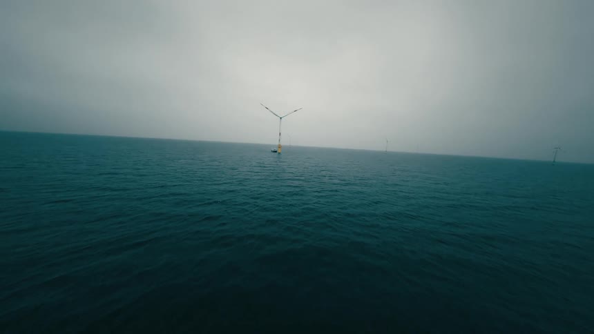 A wind turbine spins in the middle of the ocean