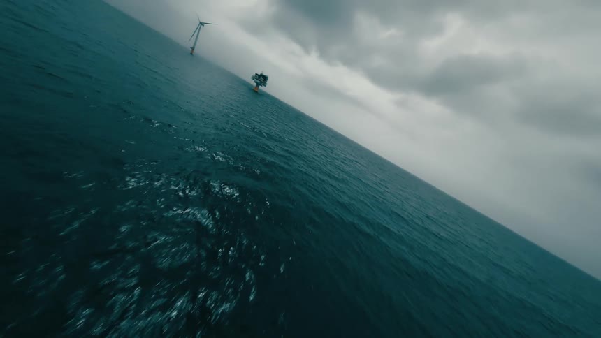 Wind turbines and a platform in the ocean on a cloudy day