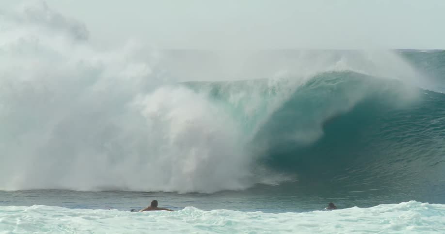 Young man wearing a black wet suit riding a white surfboard on the big waves in the ocean