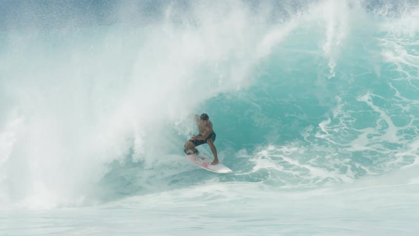 A man surfs on large waves in the ocean and then falls down