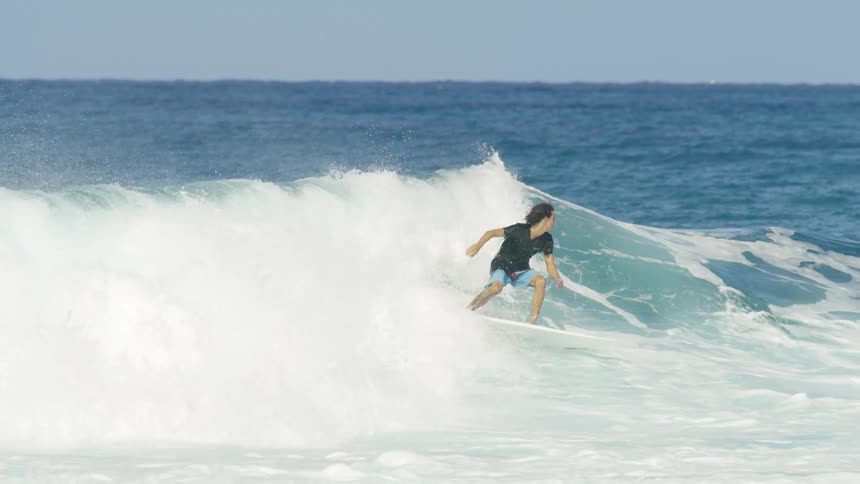 Surfer rides wave passing other people and spinning on board