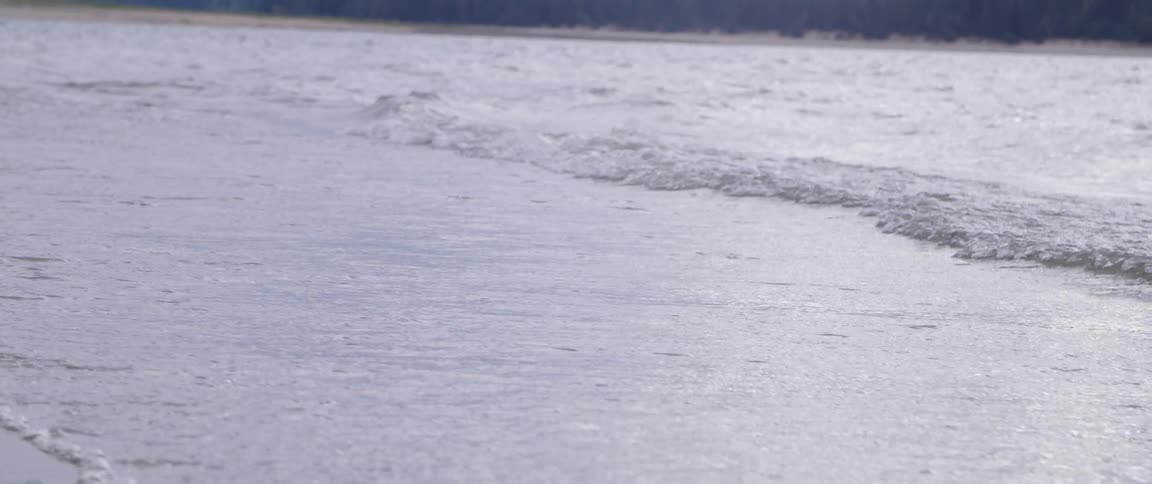 Sea waves crash on sandy beach