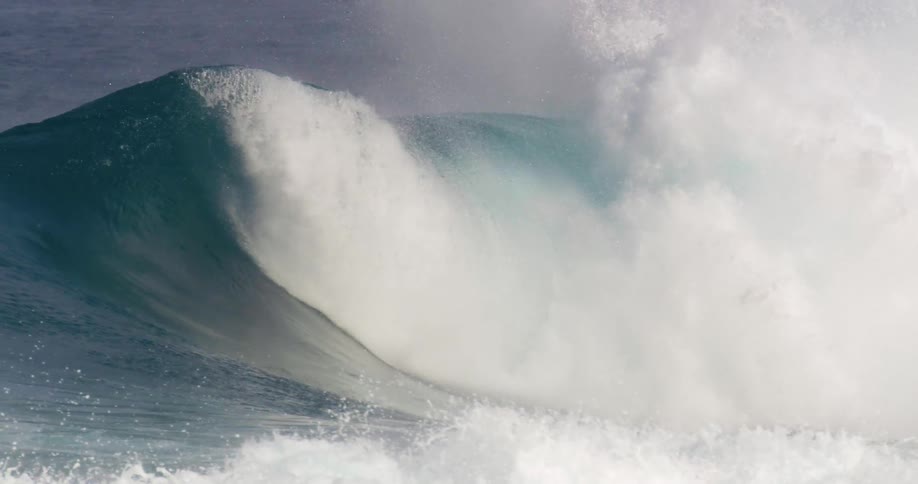 A man cheers on his friend as he rides under a tall wave