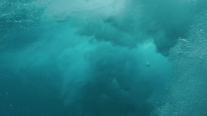A man goes underwater as he rides a boogie board in the ocean