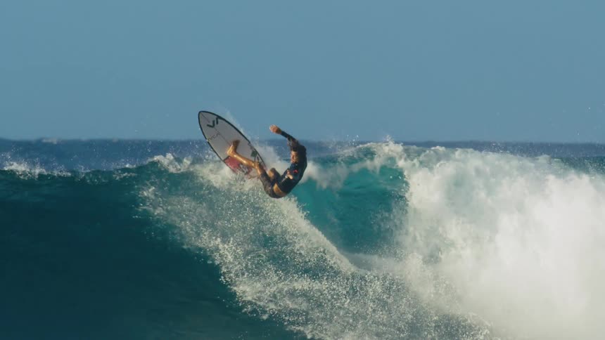 A surfer spins in the air as he rides a tall wave
