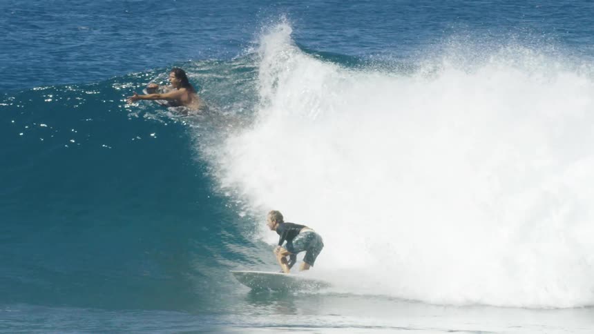 Male surfer with wetsuit and shorts rides big ocean wave