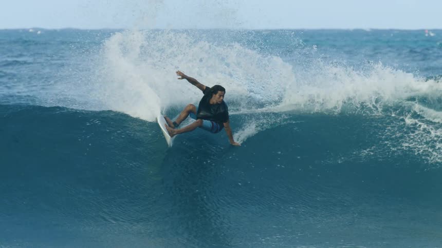 Surfer rides crashing wave as another surfer paddles up and over the swell