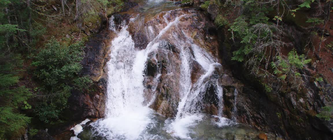 Waterfall cascades down cliffside in the woods