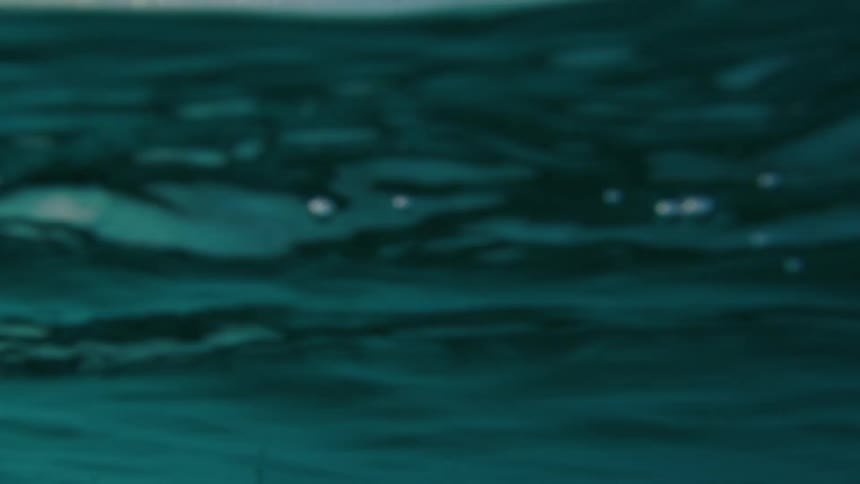 A big blue wave is rolling in splashing and then goes overhead and moves to an underwater view