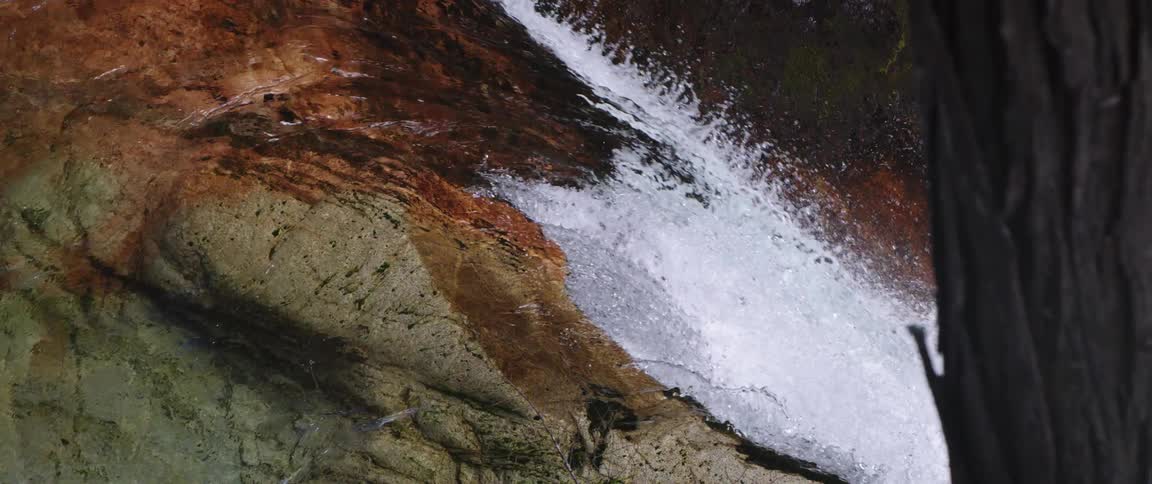 A crystal clear waterfall rushes over the side of a canyon