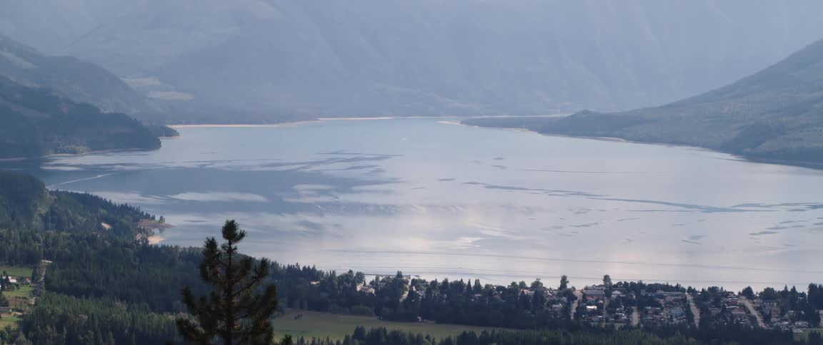 A neighborhood along the coast of an ice covered lake surrounded by mountains