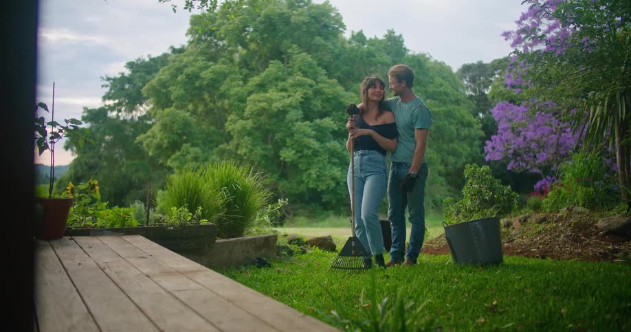 A man and woman stand closely in their rural back yard