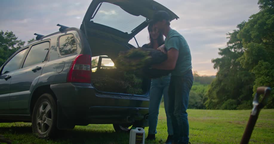 Man and woman unload rolls of turf as sun turns horizon red