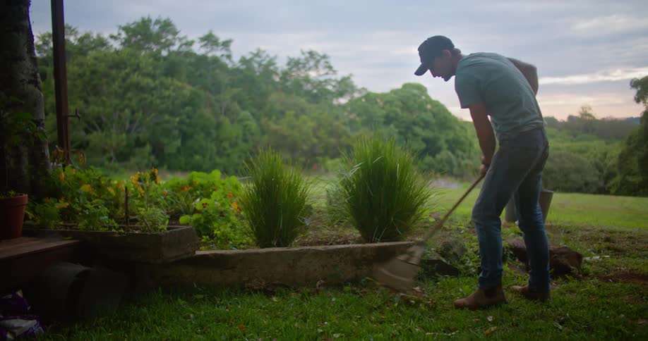 A man is raking his garden outdoors in spring