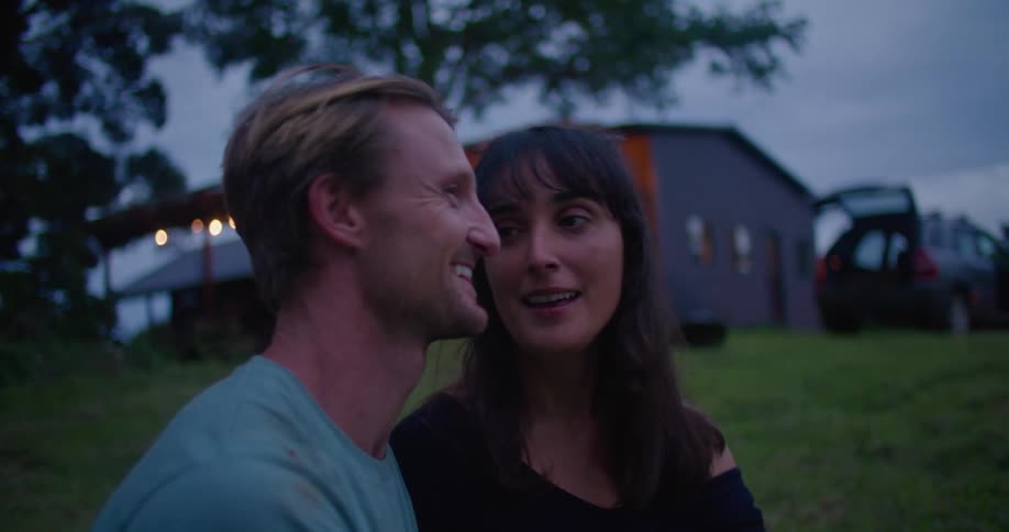 Young couple talking and kissing while standing in the backyard at evening