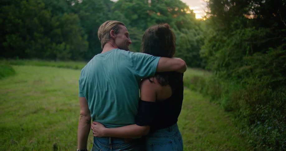 A man and woman hug closely standing in a rural yard
