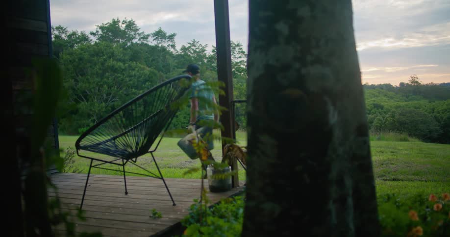 Man carries gardening equipment on the backyard at sunset