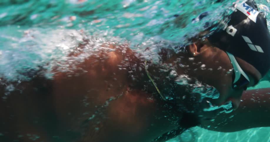 A male swimmer swimming underwater with a cap and goggles