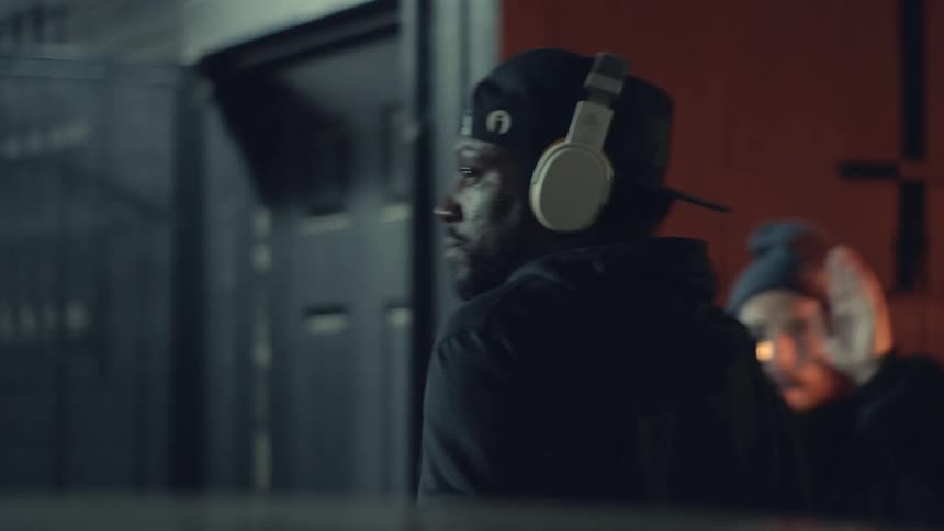 Press takes pictures as male celebrity wearing headphones steps out of vehicle
