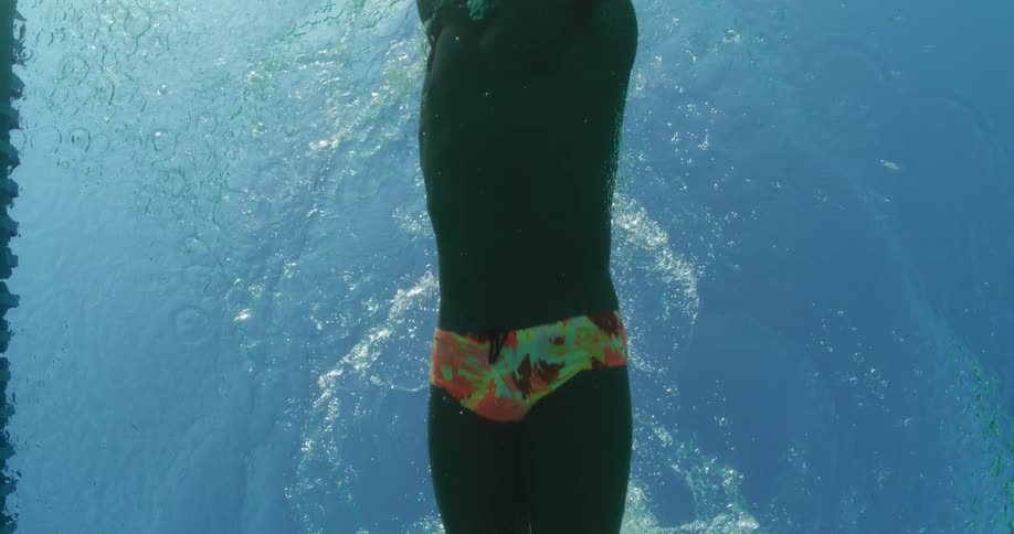 A man is swimming upwards in a pool
