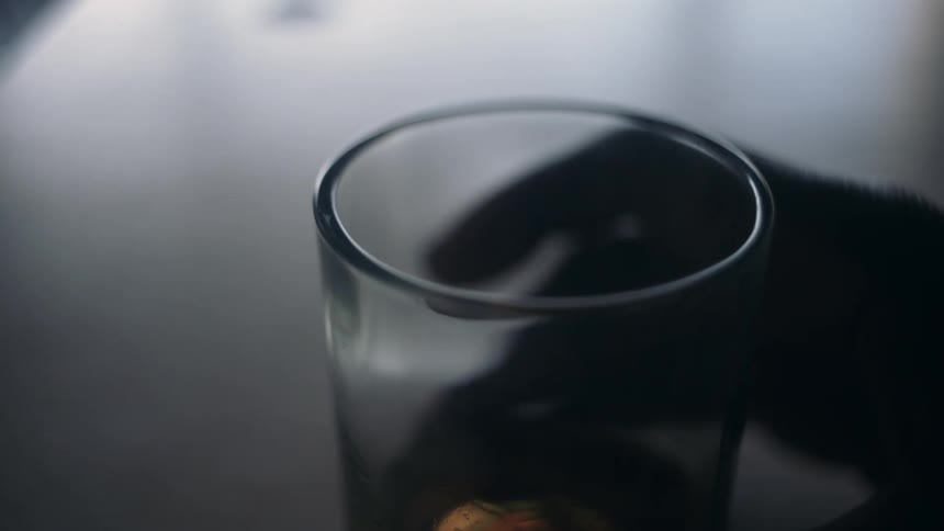 A person is lifting up a half empty glass