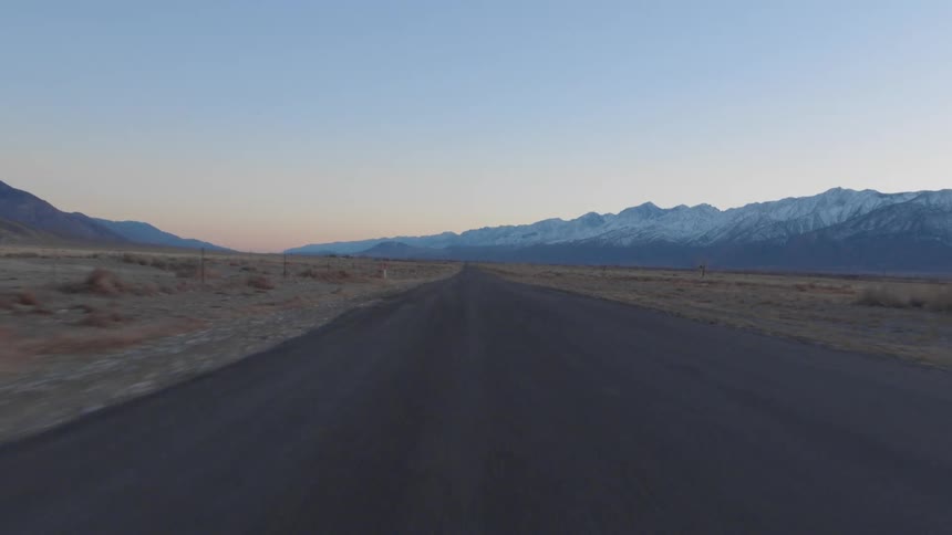 A narrow road through a vast countryside in the evening