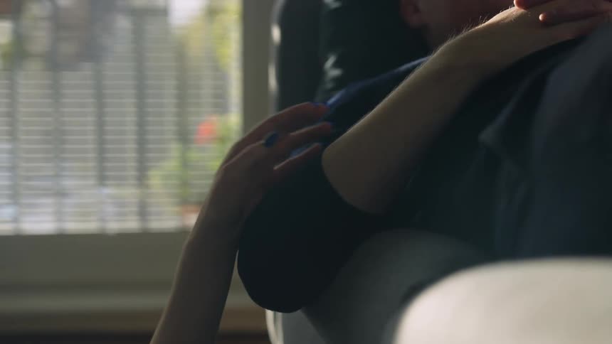 A woman reaches up and pats a sleeping mans arm