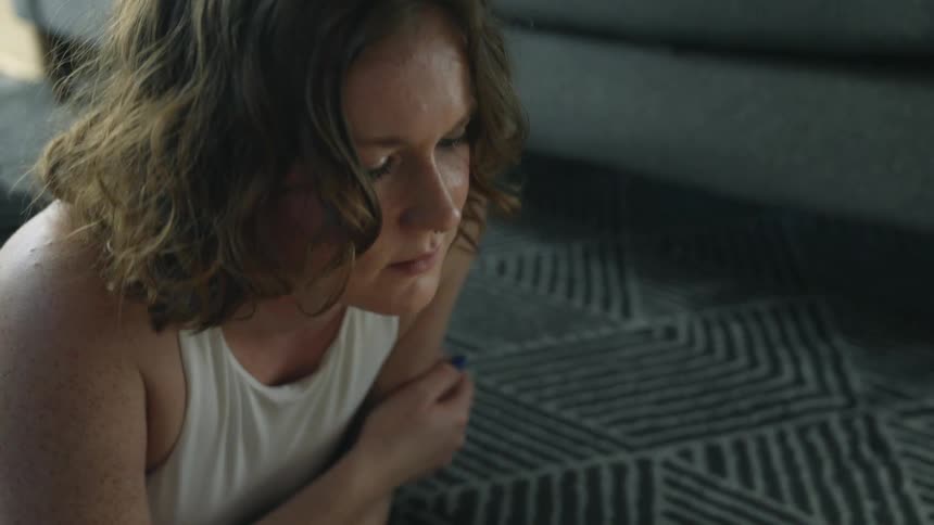 A woman lies on her stomach on the floor in her living room