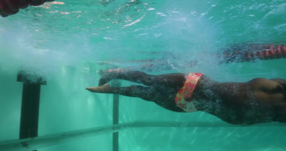A man in a colorful swimsuit swims the lanes for an indoor swimming pool