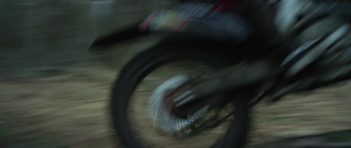 A man is riding a motorcycle fast through a forest
