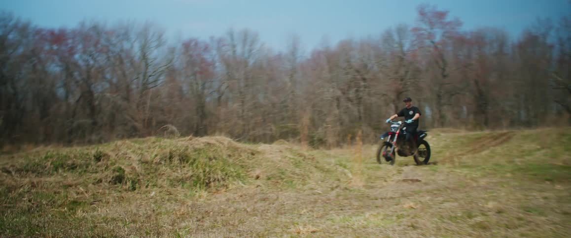 A man is dirt biking through a wooded area