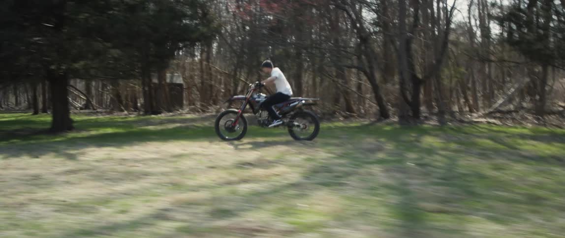 A man is riding a dirt bike through a park