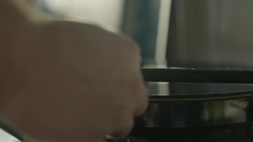 A vinyl record spins on a turntable and someone puts the needle on the record